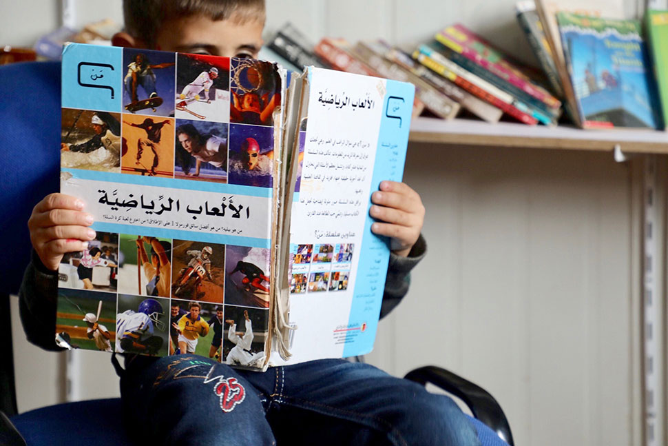 Boy in Zaatari camp reading one of the many books offered to him.